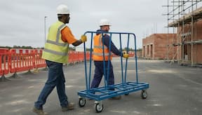 Two site operatives/labourers moving a-frame trolley accross the construction site
