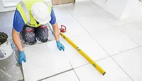 Tiler installs froor tiles in the bathroom