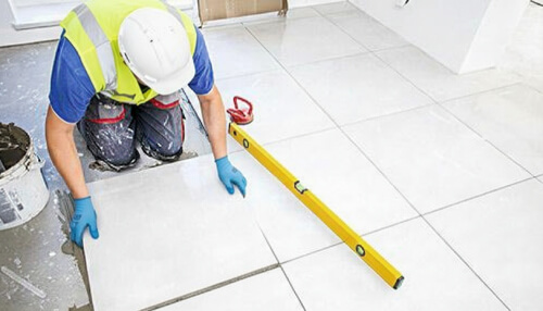Tiler installs froor tiles in the bathroom